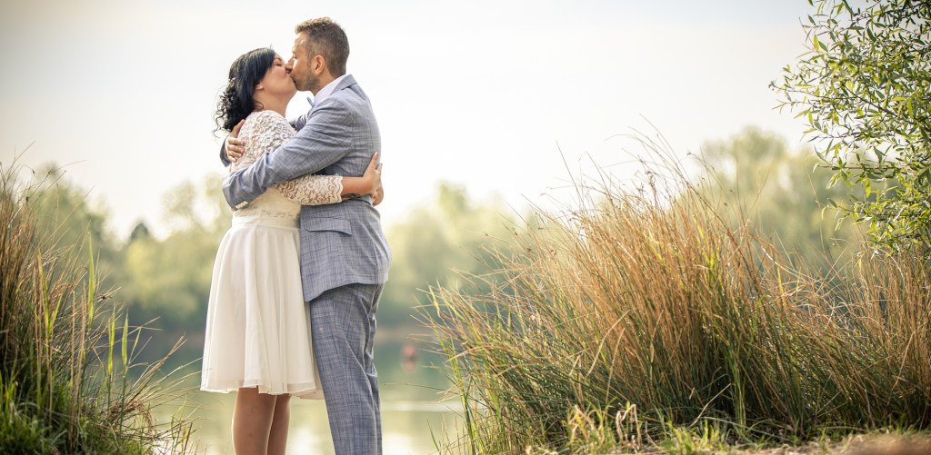 Hochzeitspaar küsst sich vor Naturkulisse